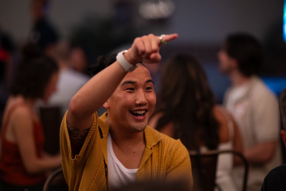 A person in a yellow shirt gestures excitedly while speaking during an animated conversation.