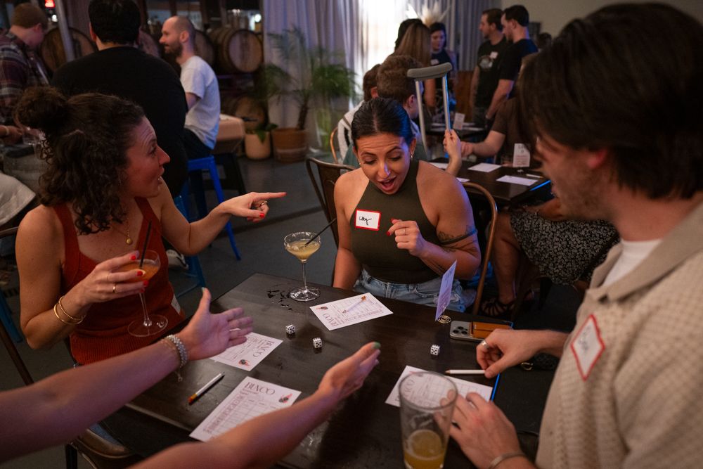 People sitting at tables play a card game together during a social gathering.