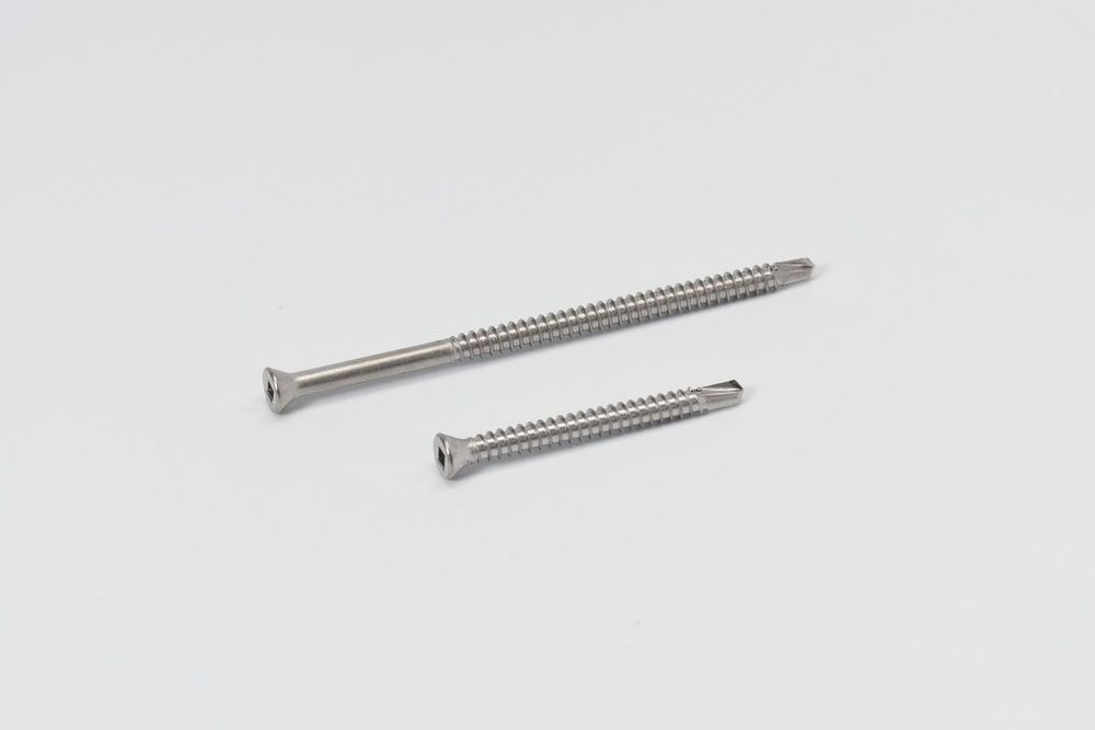 Multiple silver wood screws of varying lengths arranged in a row on white surface.