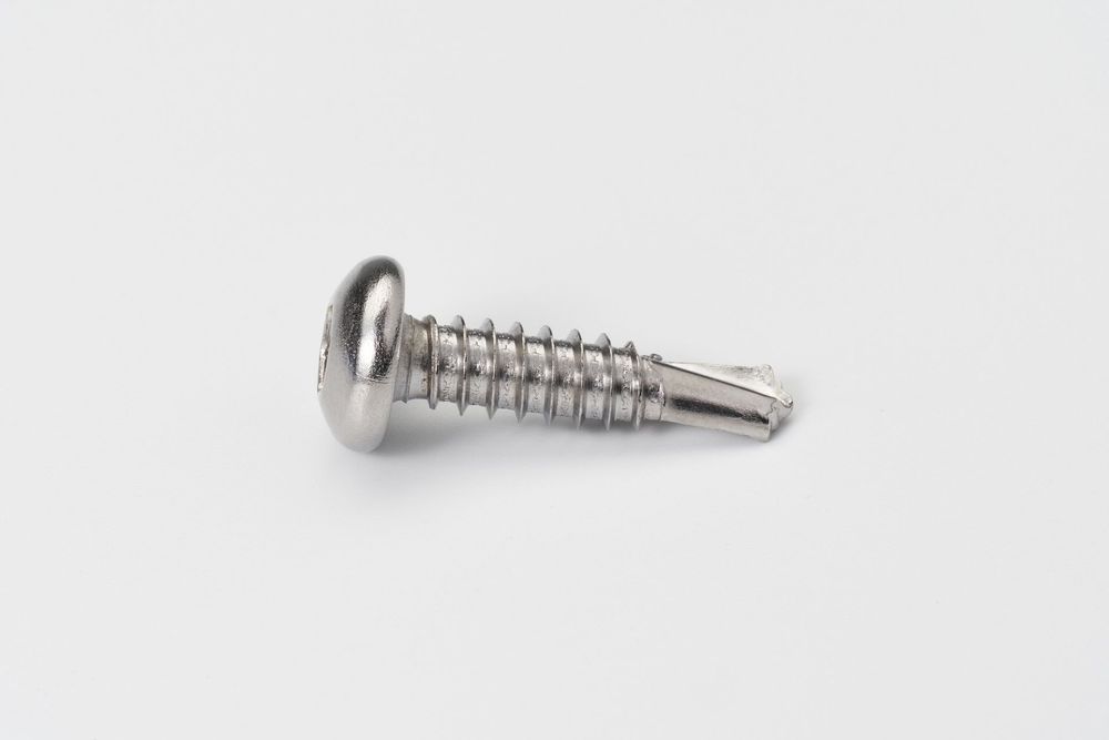 Close-up view of silver metal screws and hardware components arranged on white background.