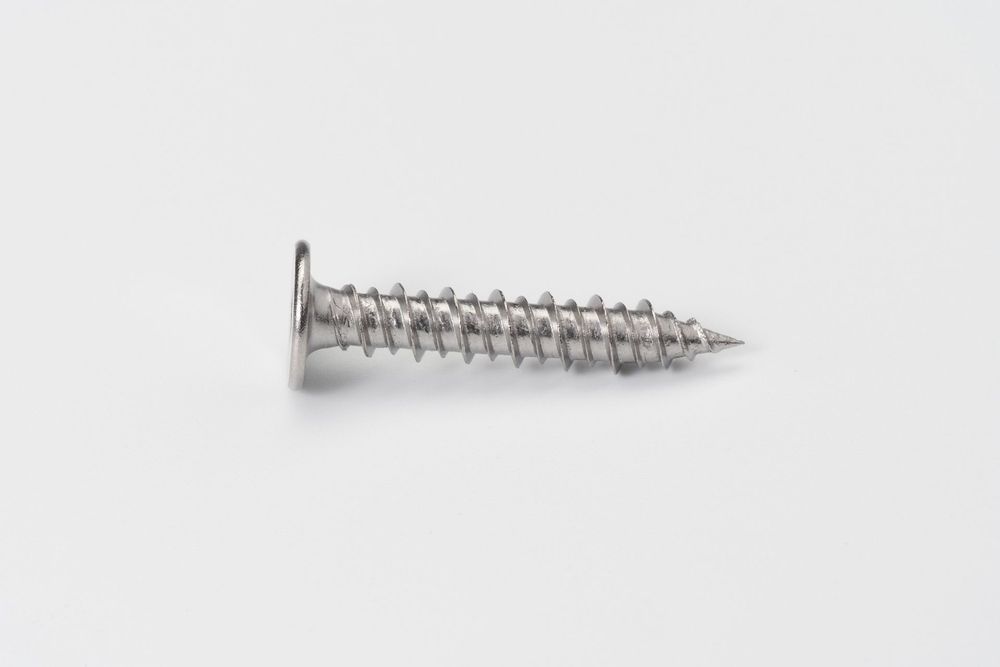 A silver metal wood screw with Phillips head and coarse threading isolated on white background.