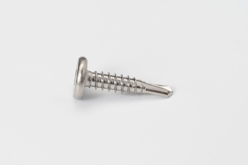 A silver self-drilling metal screw with flat head and threaded shaft isolated on white background.