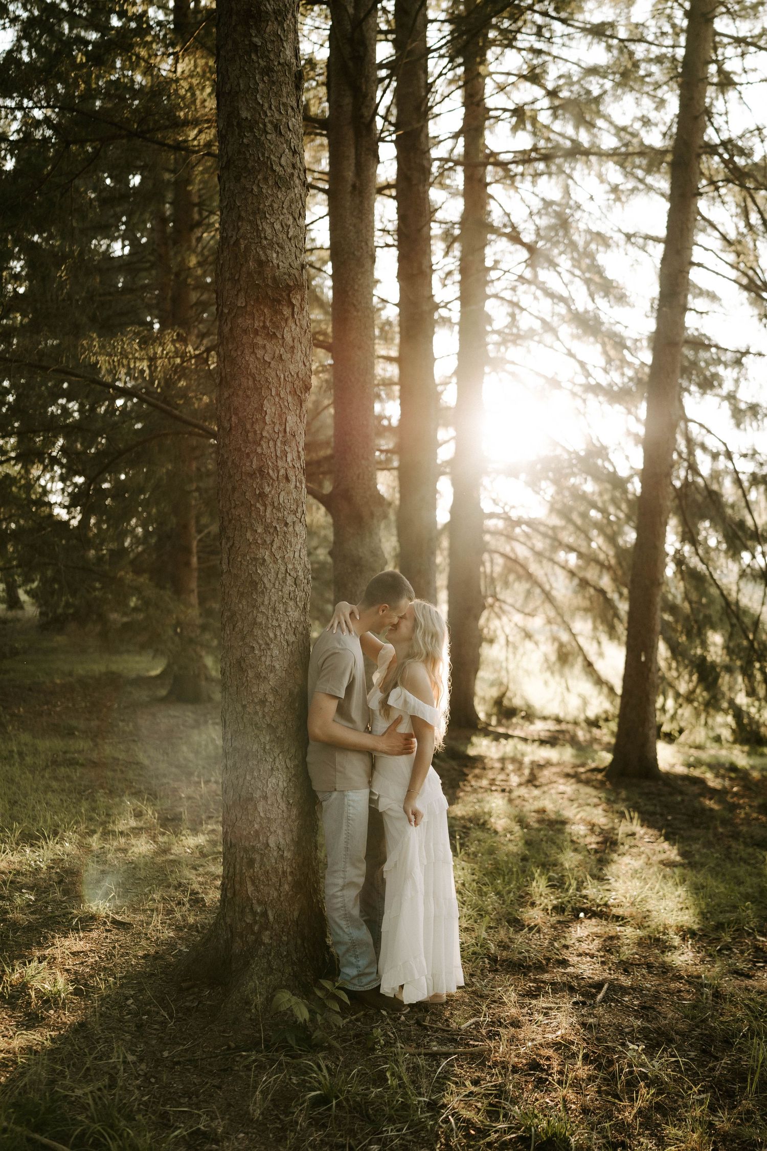 Two women in white tops pose playfully near waterfall in lush forest.