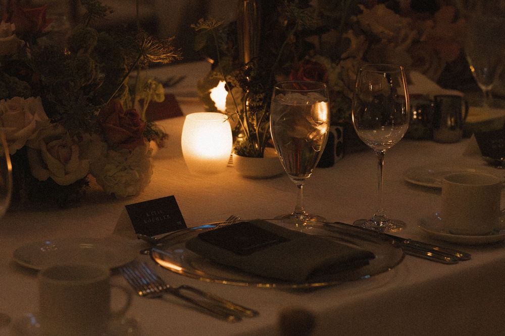 Elegant table settings at a formal dinner event with glowing candlelight and wine glasses creating an intimate atmosphere.