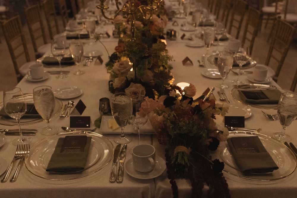Elegant table settings with white linens, charcoal plates, and floral centerpieces at a formal dining event.