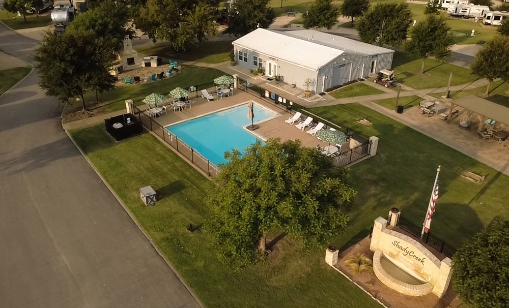Aerial view of a community pool and recreational area surrounded by green lawns and residential buildings.