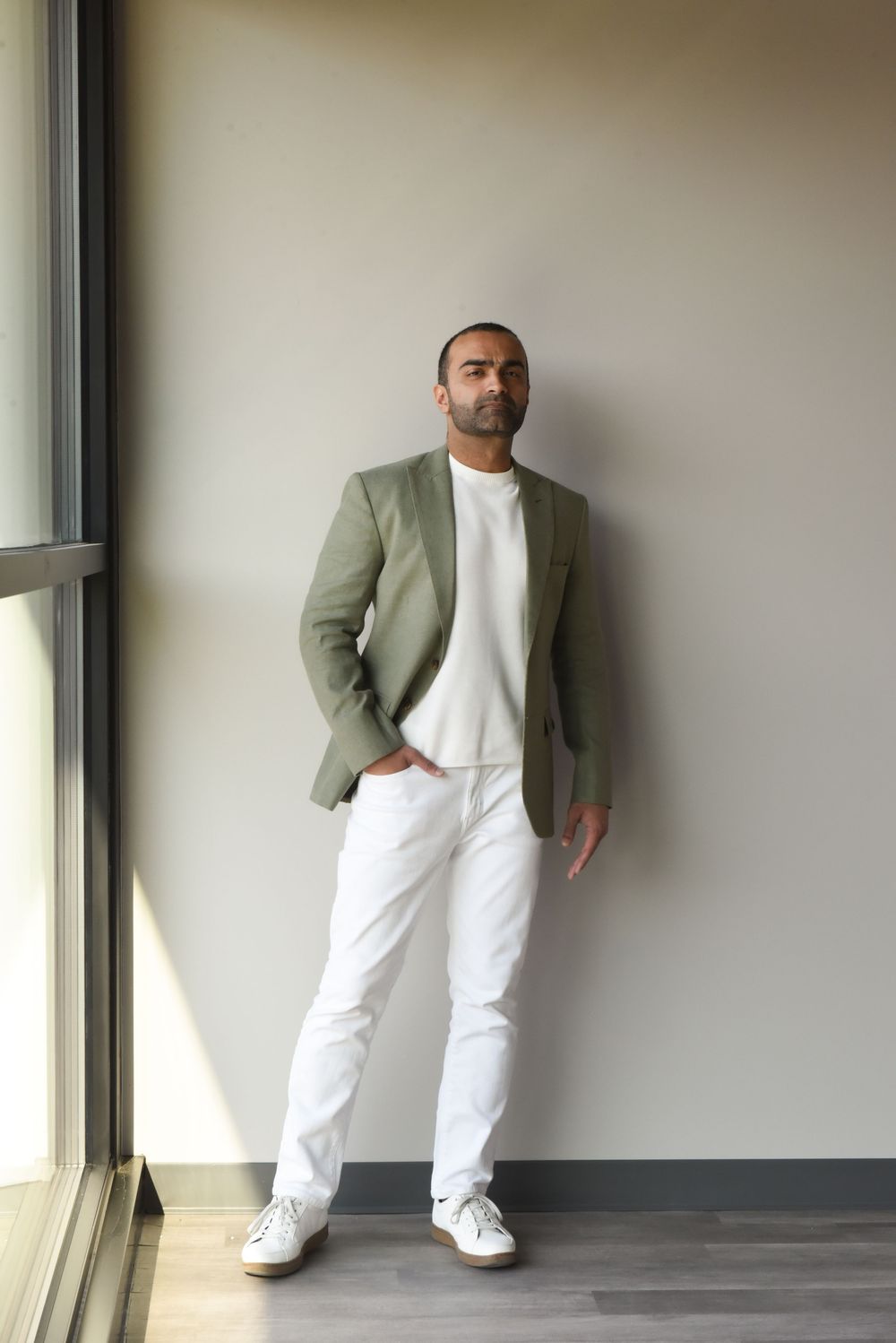Fashion photo series showing a casual outfit combination of sage green blazer with white t-shirt and pants against a wall.