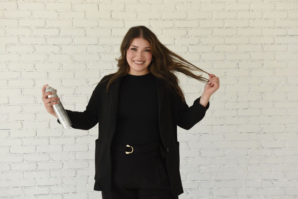 Person in black outfit dancing joyfully against white brick wall background.