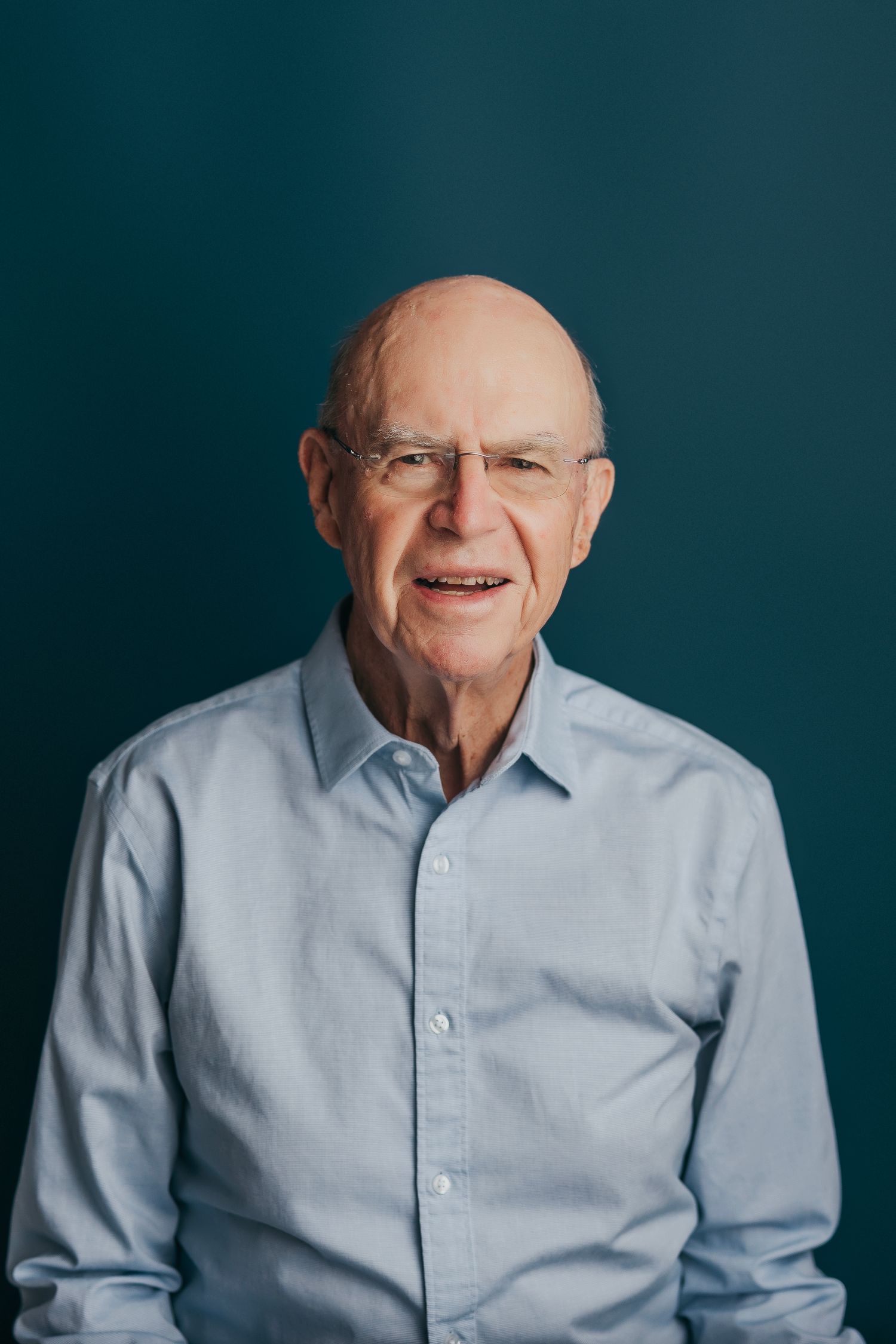 A senior in a light blue button-down shirt shown in four progressive shots against a dark teal background.