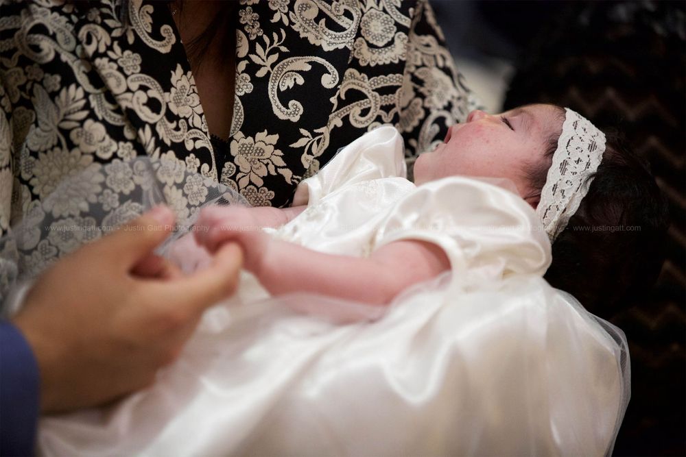 Close-up shots of a baby in an ornate white christening gown with lace details.