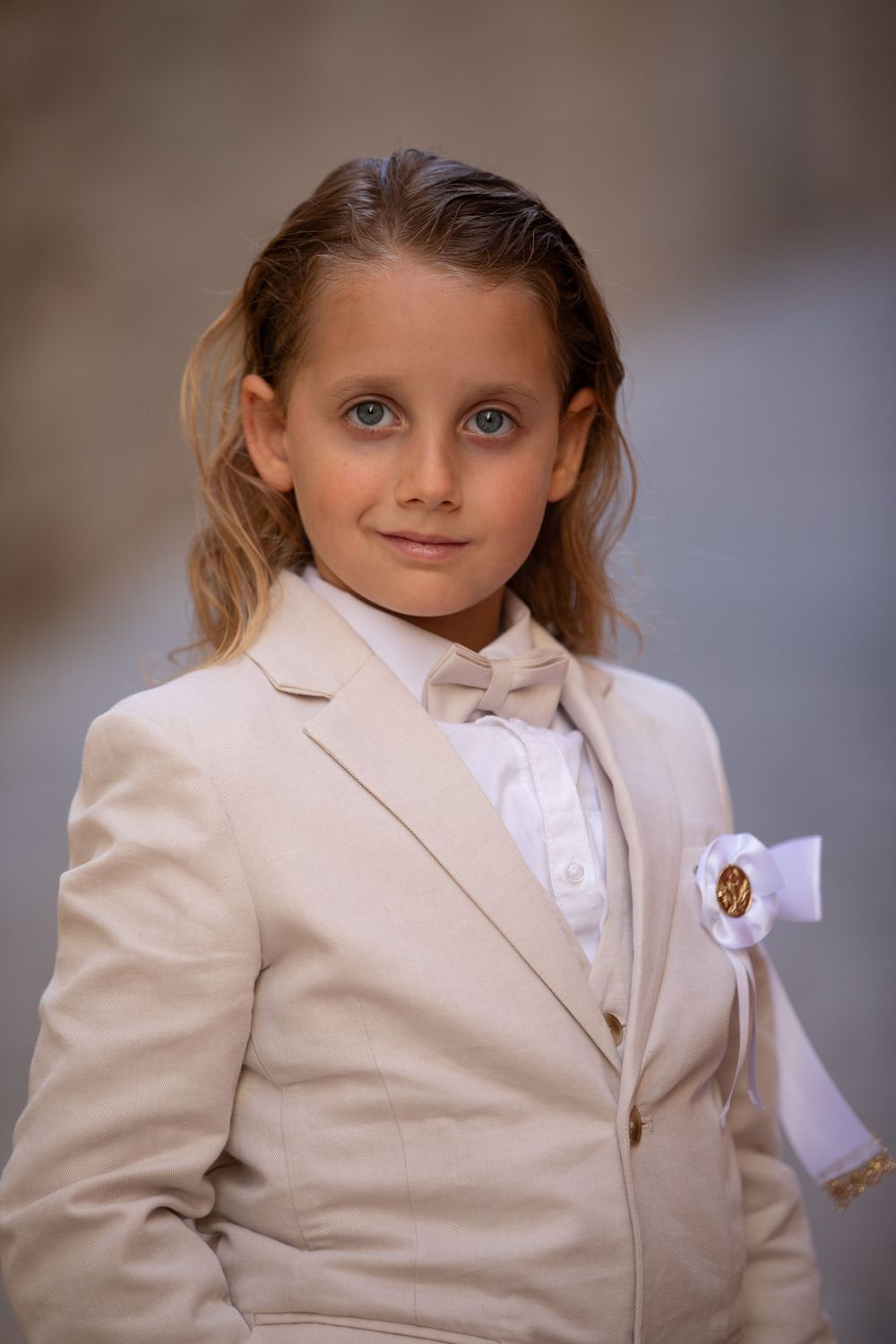 Young child wearing a formal beige suit with white shirt and bow tie.