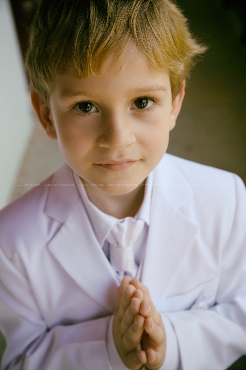 Portrait series of a young child in white formal attire with gentle expressions.