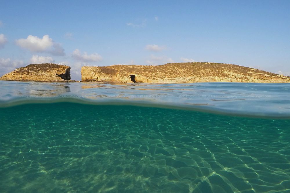 Panoramic seascape with rocky coastline and crystal clear turquoise waters.