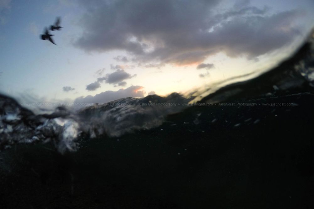 Dramatic mountain landscape silhouette at sunset with dark storm clouds.