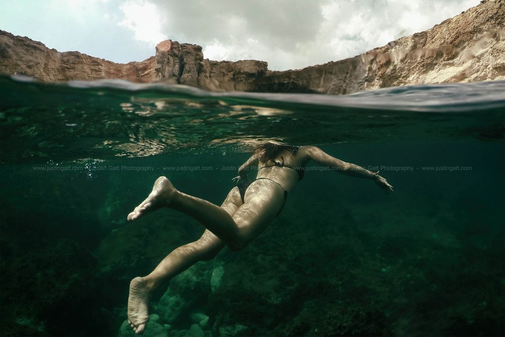 Split underwater view of rocky cliffs and clear Mediterranean waters.
