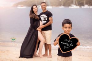 A series of beach photos showing pregnancy announcement with black t-shirts and text on the sand at sunset.