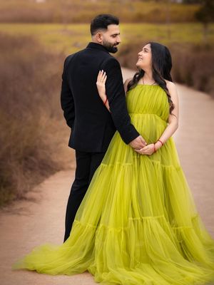 A couple in formal attire poses romantically on a path, with the woman wearing a flowing chartreuse tulle gown.