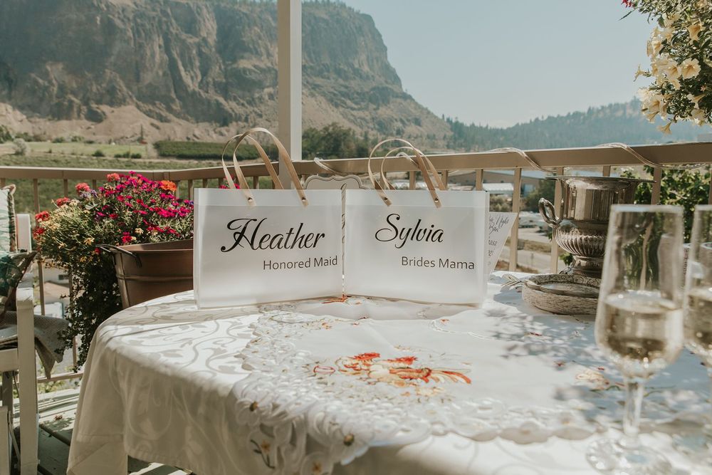 Personalized wedding gift bags for Heather and Sylvia on a table with mountain views and champagne.