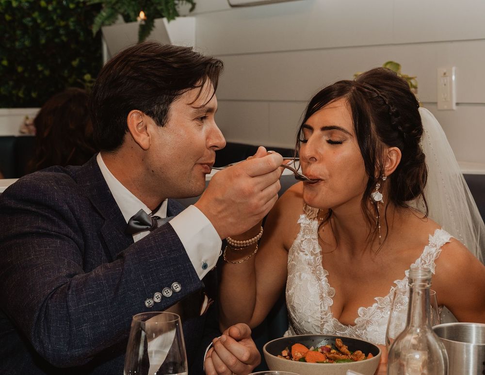 Bride and groom sharing a romantic moment as the groom feeds his bride at their wedding reception.