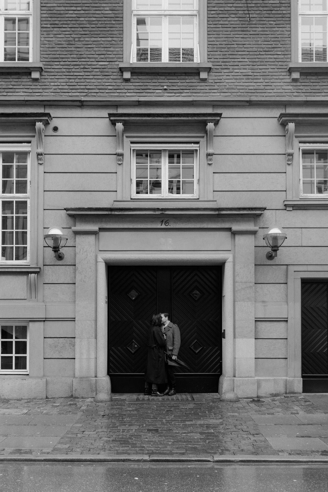 Monochromatic view of an ornate building exterior with multiple entrances and decorative stonework details.
