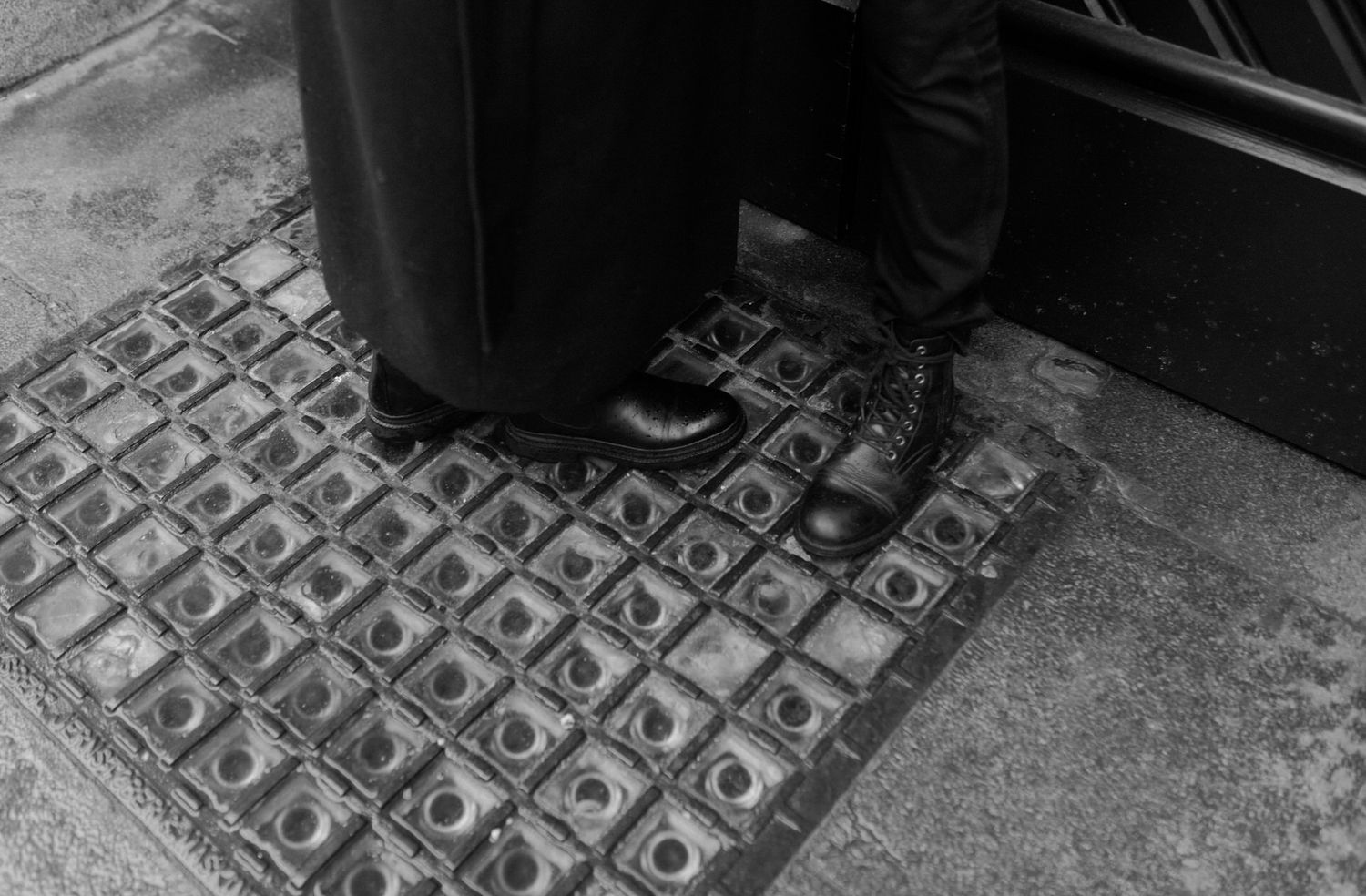 Feet walking on a decorative patterned floor tile with geometric shapes in black and white.