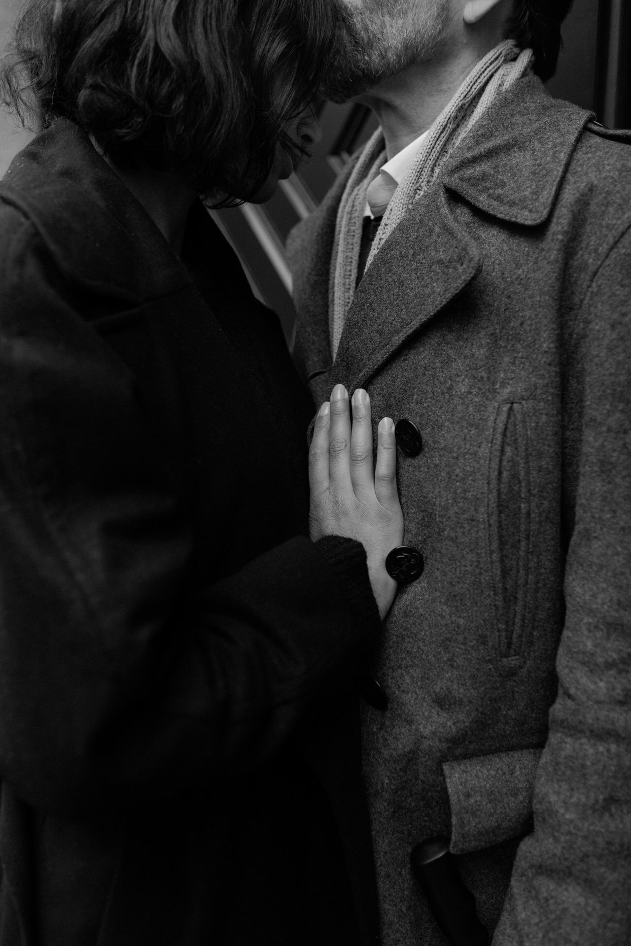 A black and white vintage photograph shows a couple embracing in a romantic moment.