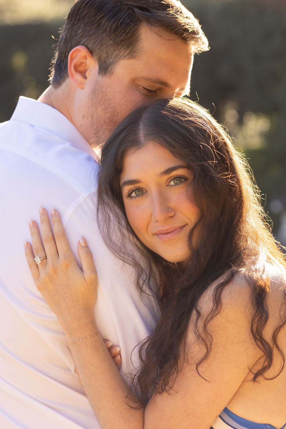 A couple shares an intimate moment in warm sunlight while dressed in white.