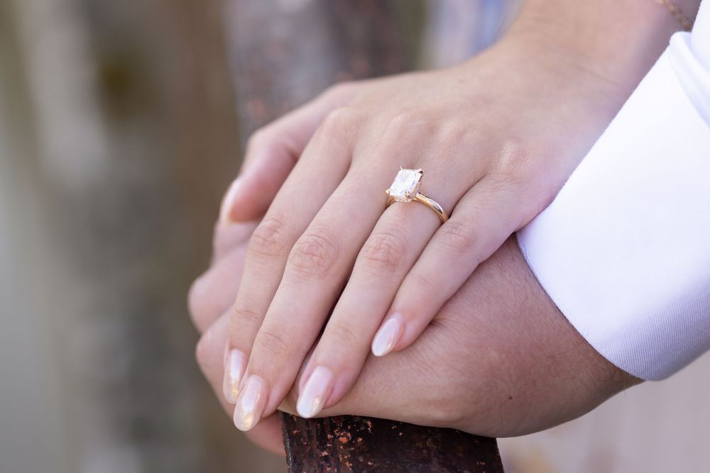 Close-up view of hands exchanging wedding rings during a traditional ceremony.