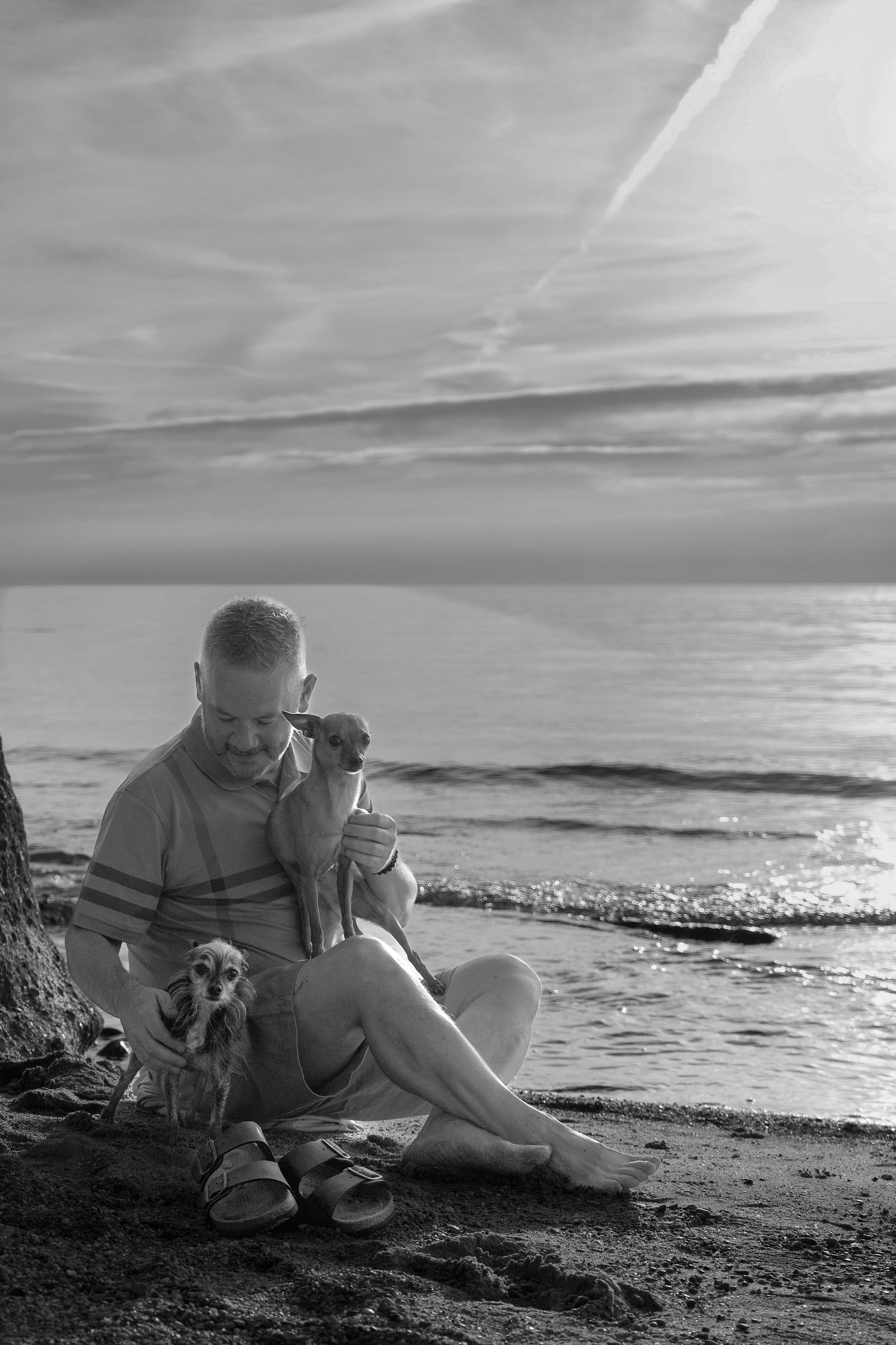 A series of black and white beach photos showing a couple relaxing on the sand at sunset.