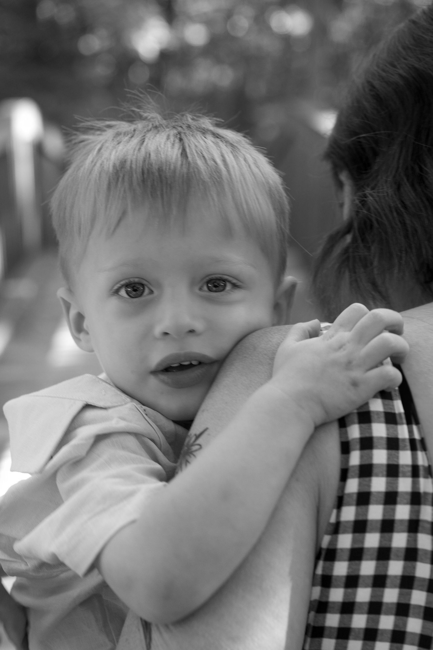 A black and white photo sequence shows a child leaning against someone wearing a checkered shirt in different poses.