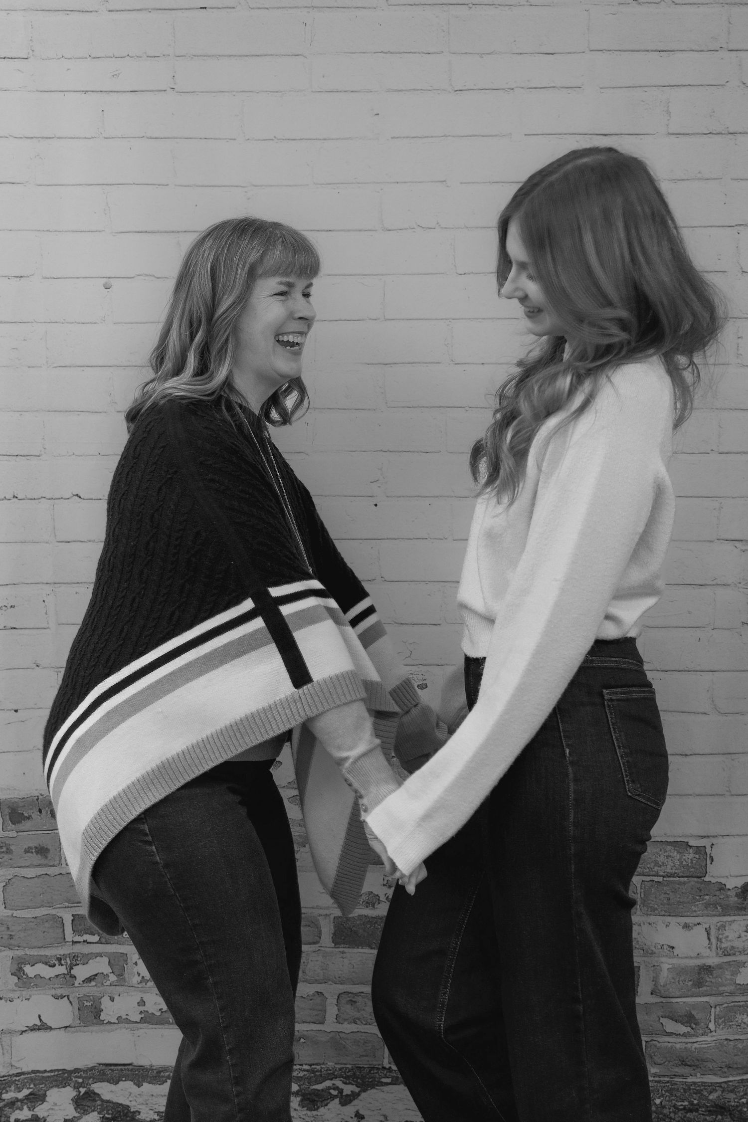 A sequence of black and white photos showing two people playfully interacting against a brick wall.