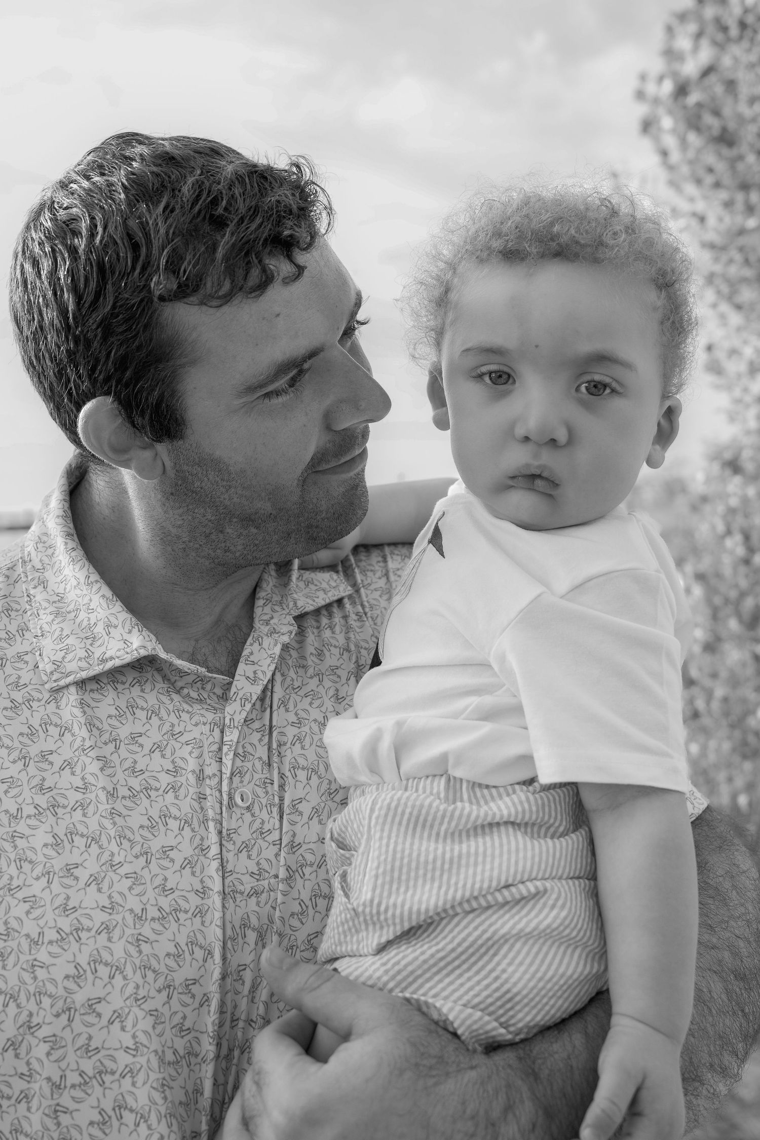 A black and white photo series showing tender moments between a parent and baby in casual clothing.