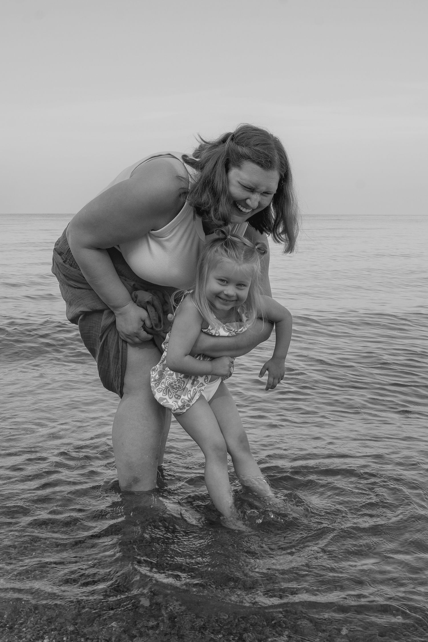 A joyful sequence of two people playing and splashing together in ocean waters captured in black and white photography.