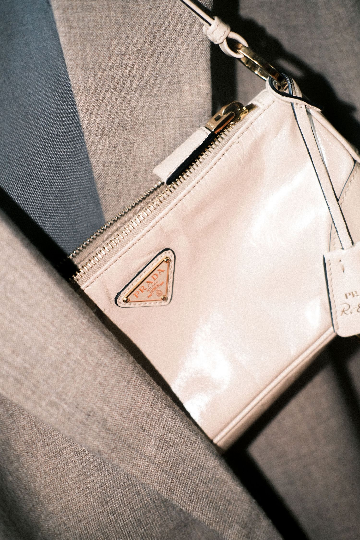 A series of close-up shots showing different angles of a white leather Prada wallet with zipper closure.