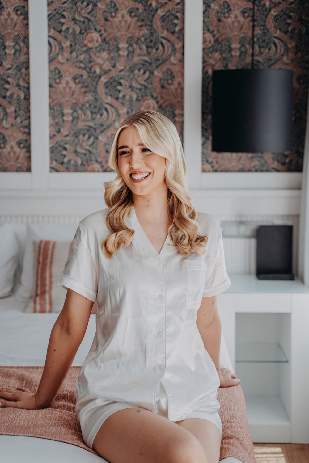 Interior boudoir photography session with floral wallpaper and white decor.