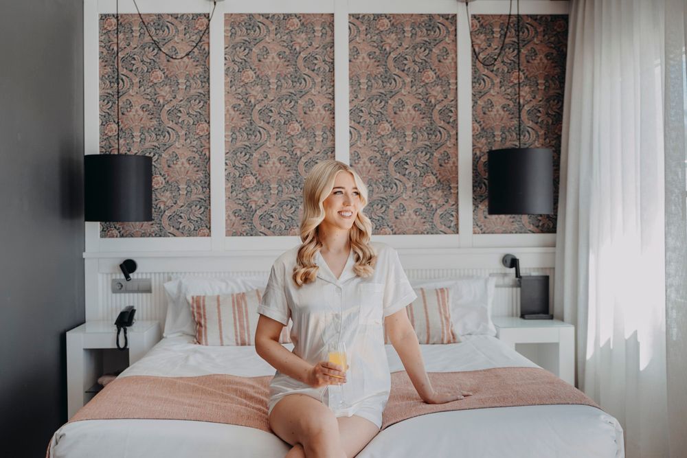 Elegant bedroom interior with floral wallpaper, white bedding, and soft natural lighting through sheer curtains.