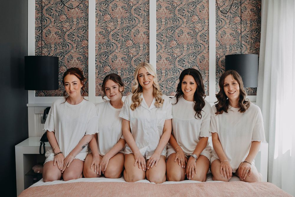 Group photo session in matching outfits against floral wallpaper backdrop.