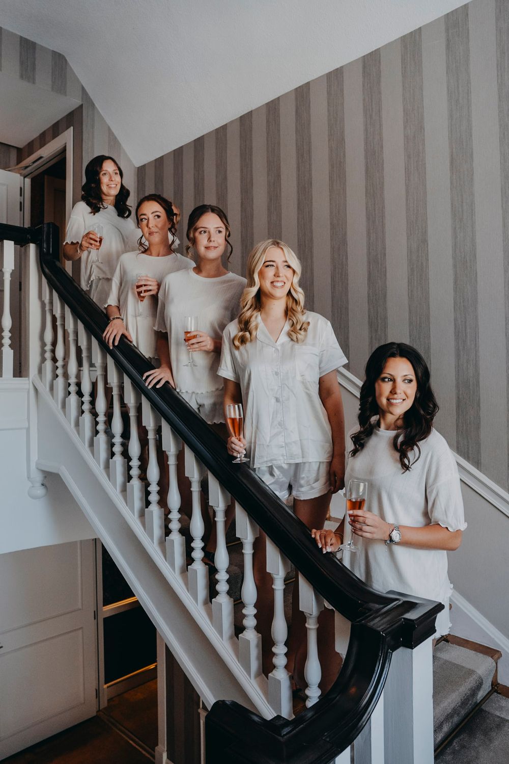 Group wearing matching white outfits posing playfully on a staircase.