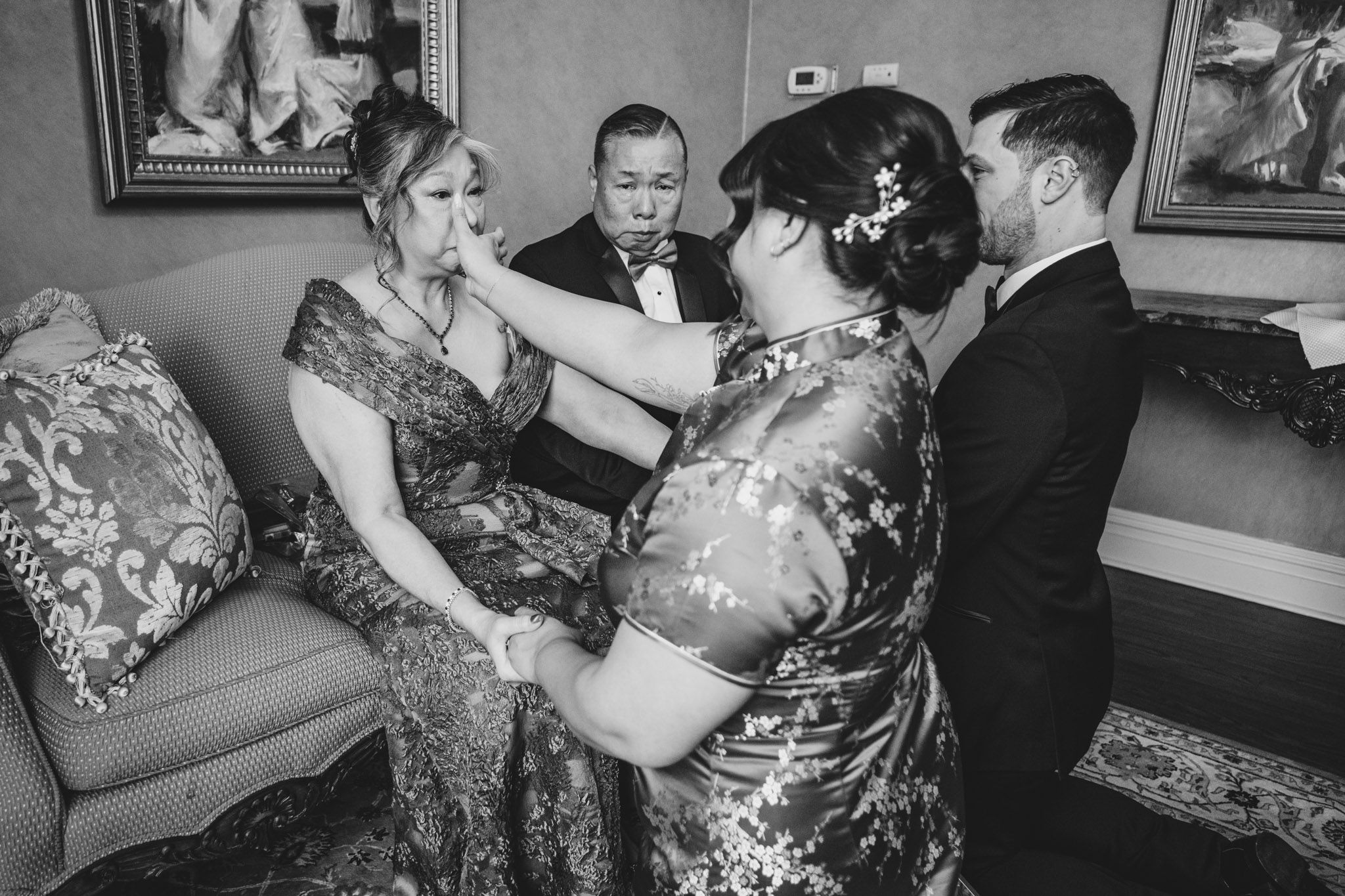 Black and white photo of wedding party members sharing an intimate moment during celebrations.