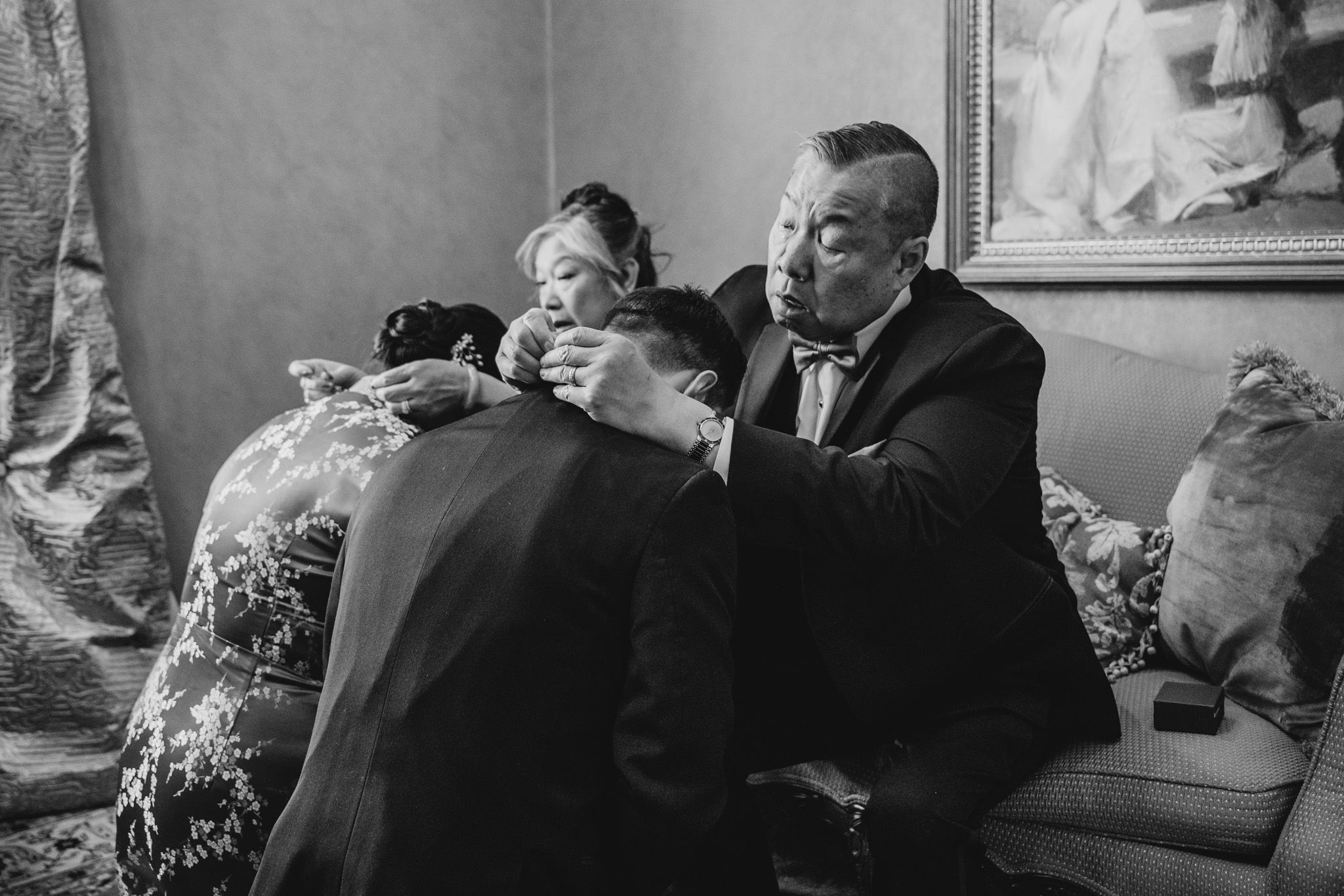 Emotional black and white photograph of wedding guests embracing during celebration.