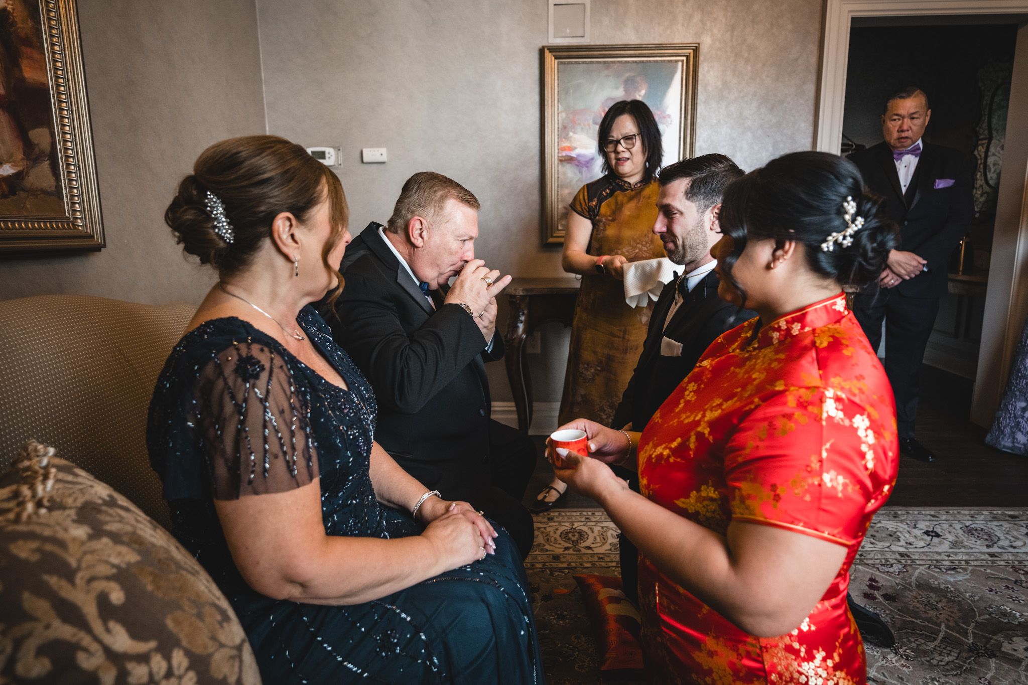 Wedding party gathered in an elegant room with traditional Chinese and Western attire.