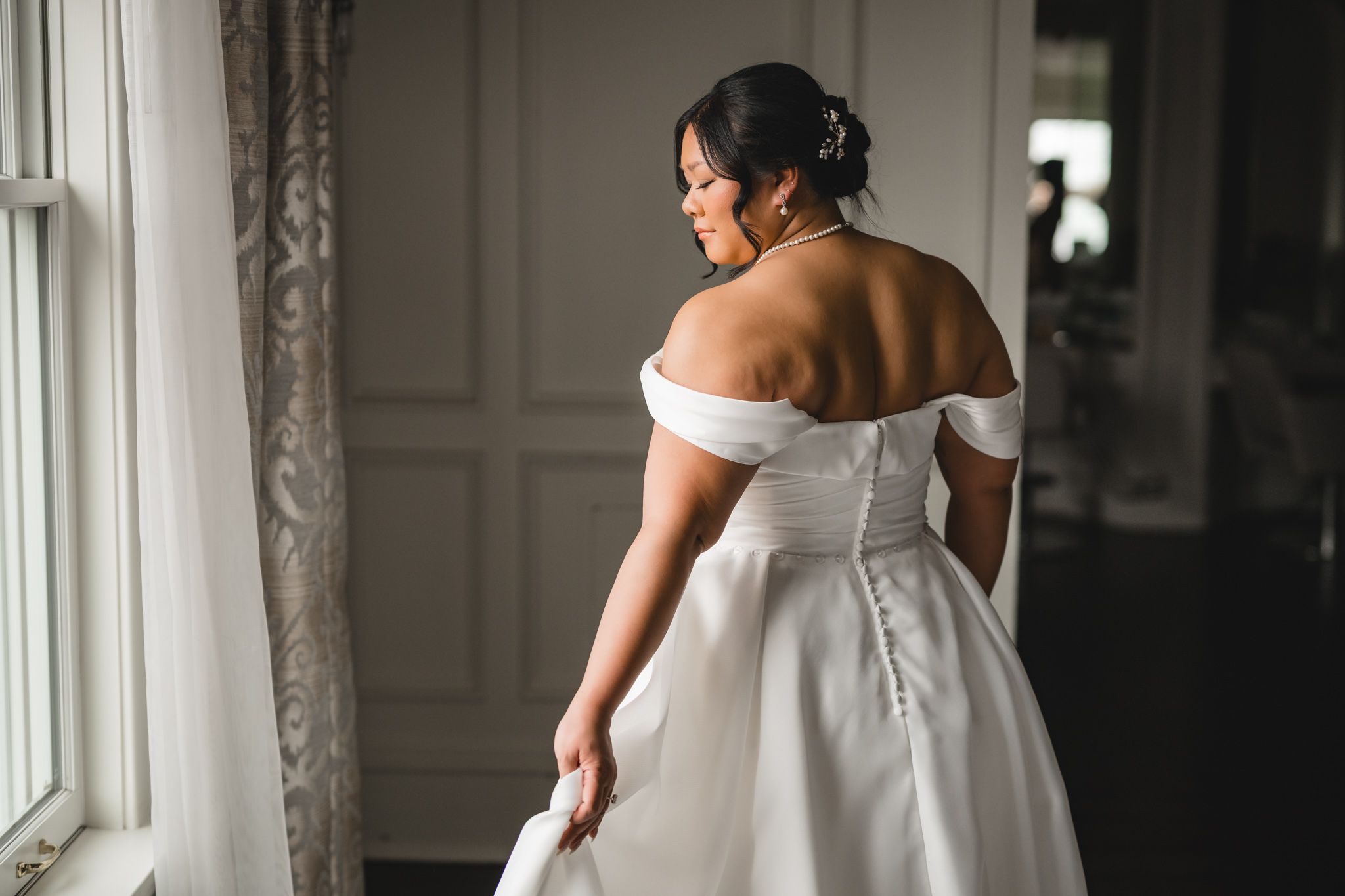 Elegant white wedding dress details photographed in window light.
