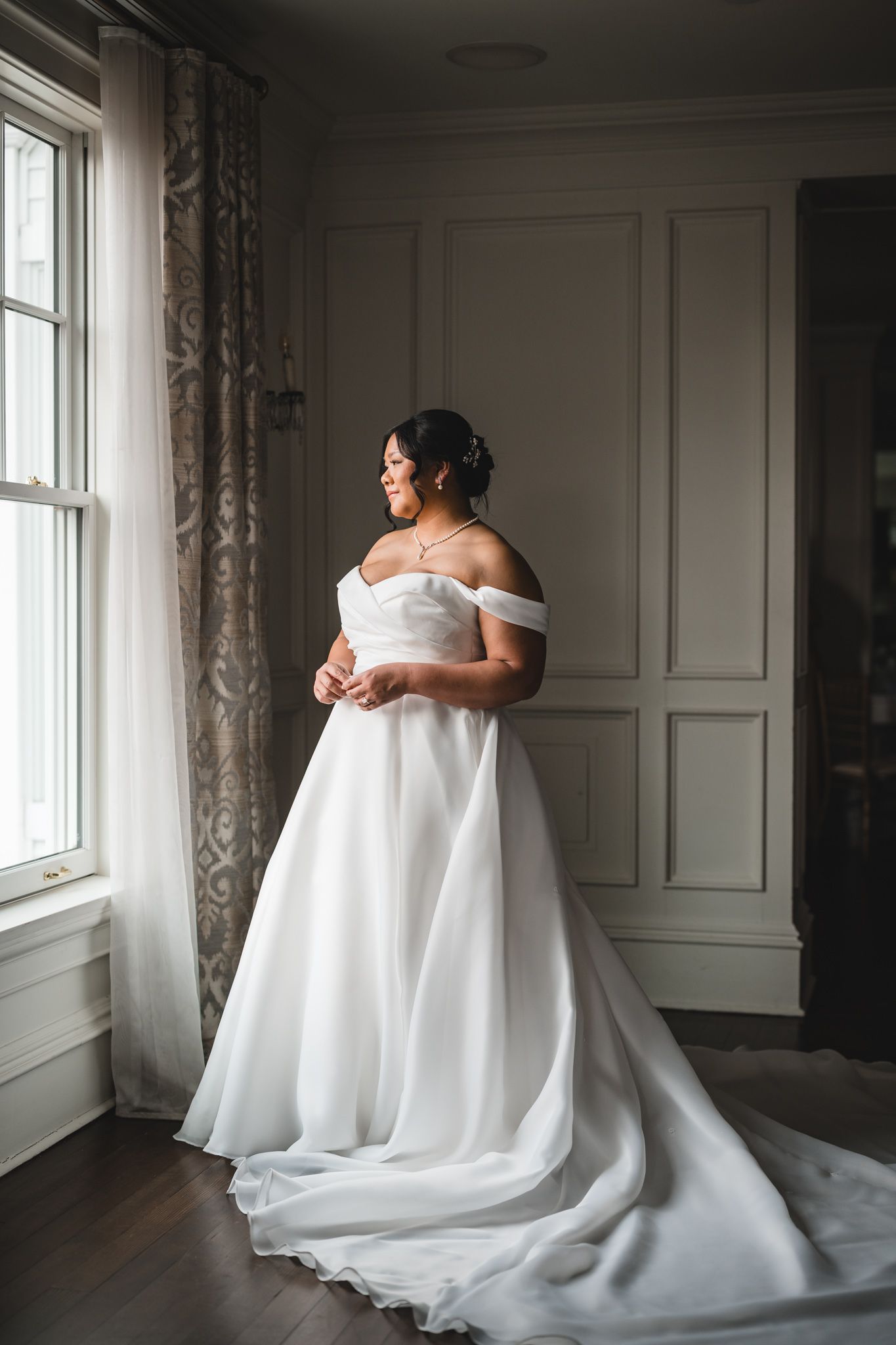 Dramatic bridal portraits showcasing flowing white wedding gown against dark interior.