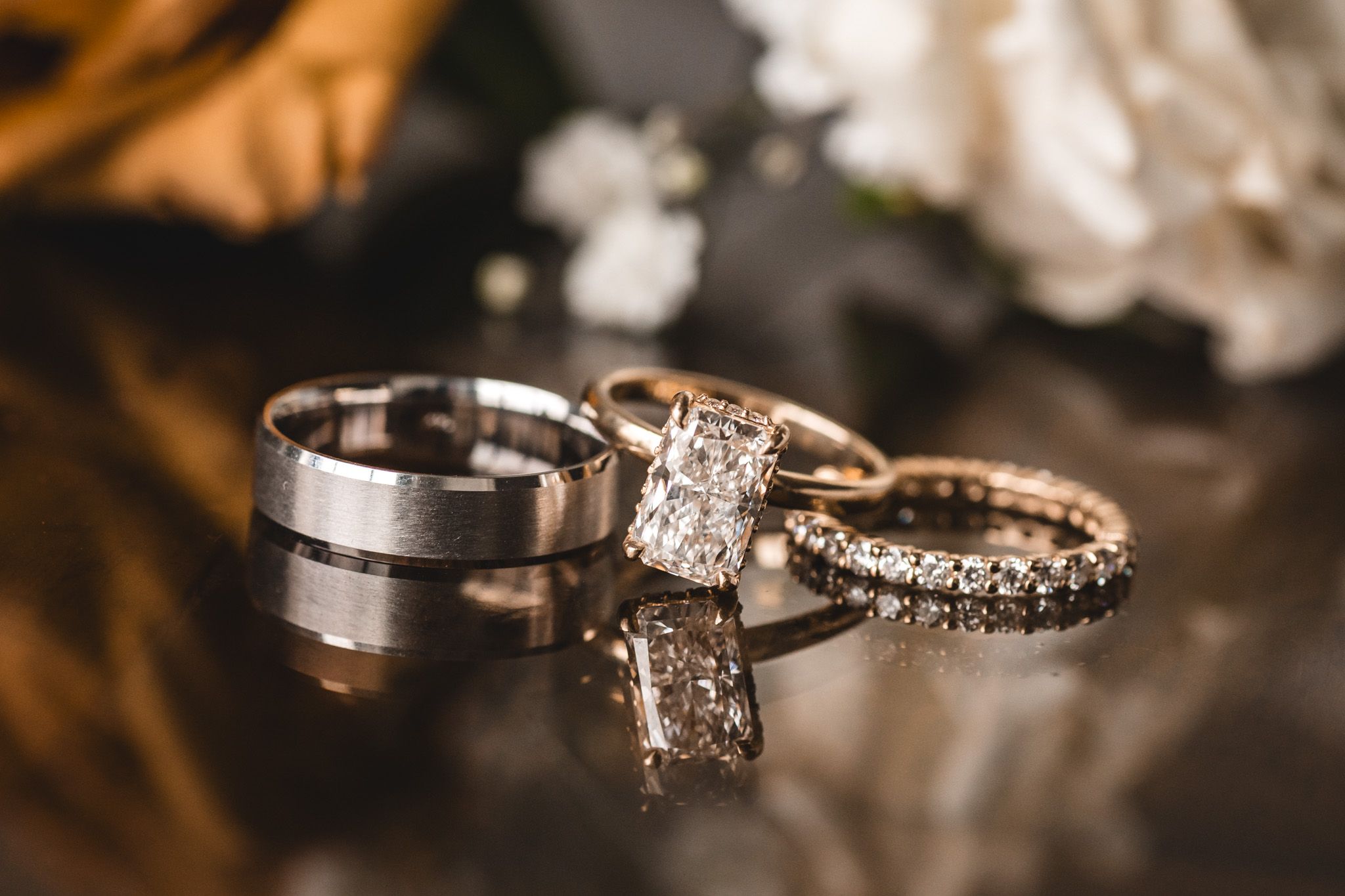 Close-up of sparkling diamond wedding rings and bands arranged on reflective surface.