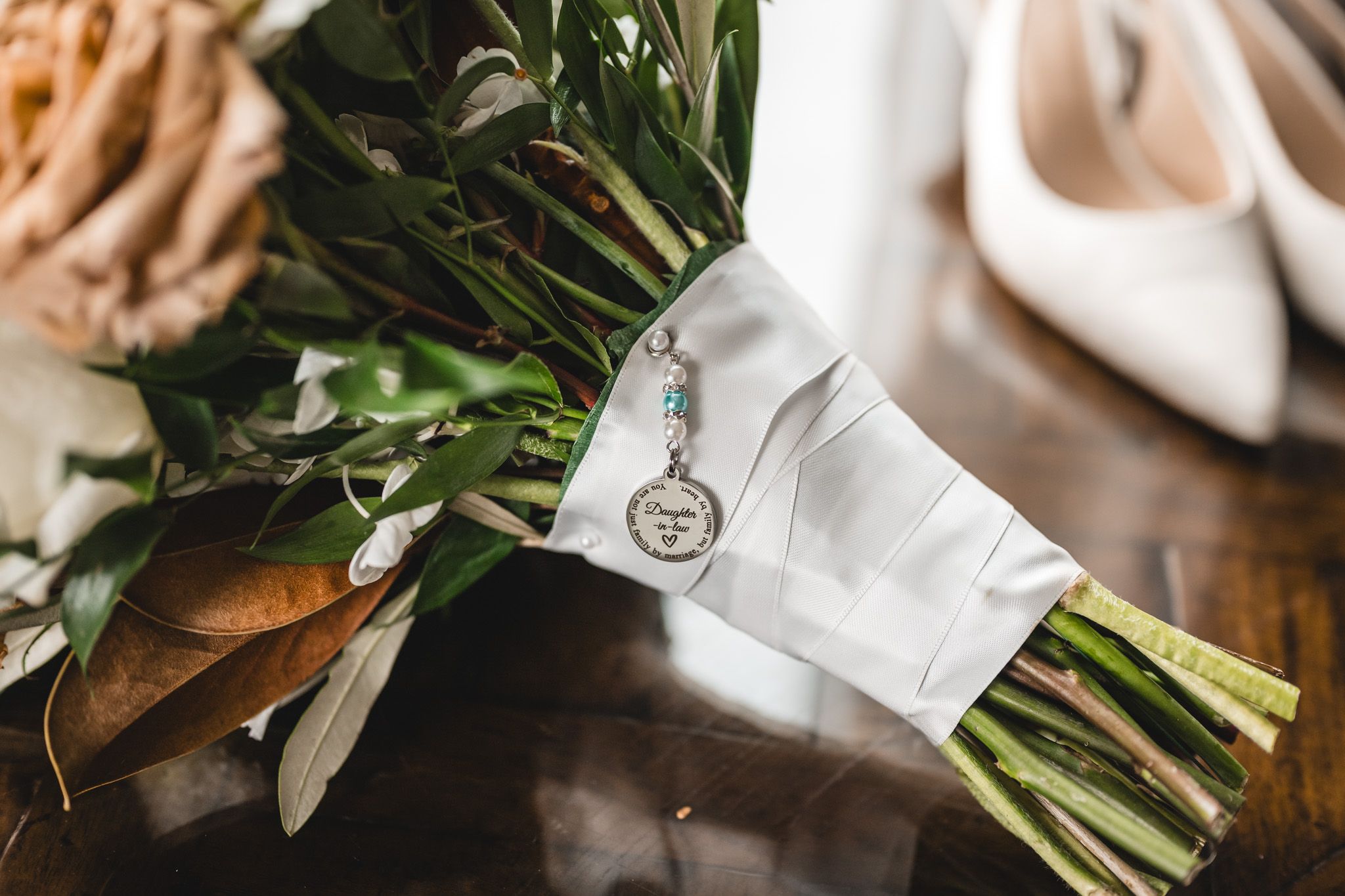 Elegant white bridal bouquet with roses and greenery against dark background.