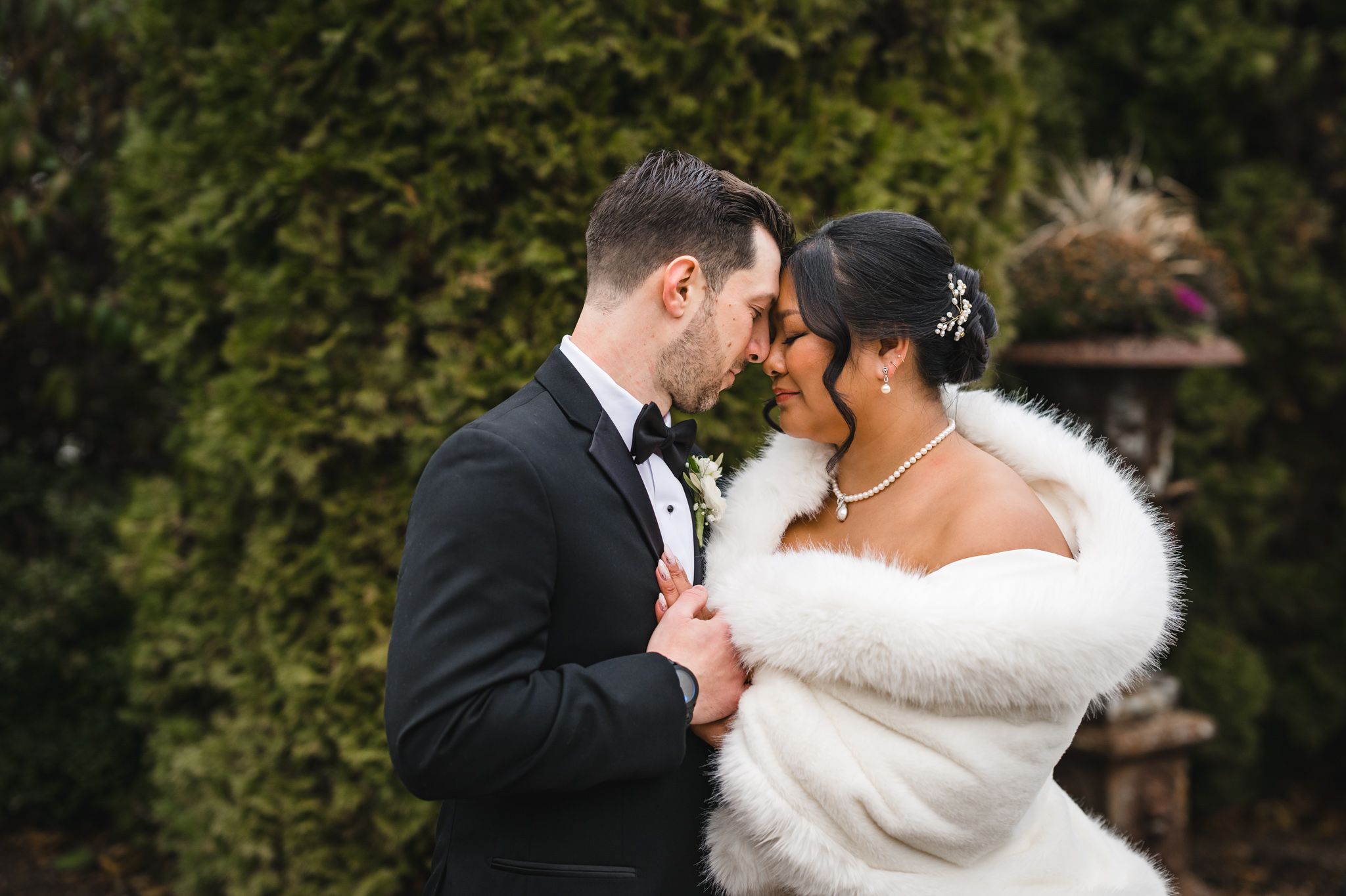 Intimate wedding moment captured with couple in formal attire against garden backdrop.