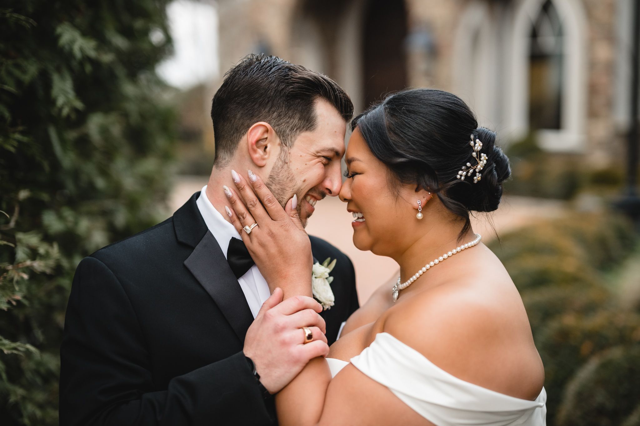 Emotional wedding moment captured with couple touching foreheads outside chapel.