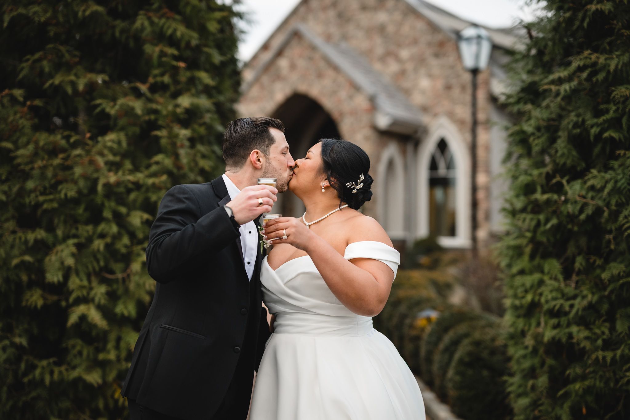 Joyful wedding couple sharing intimate moment in front of stone church entrance.