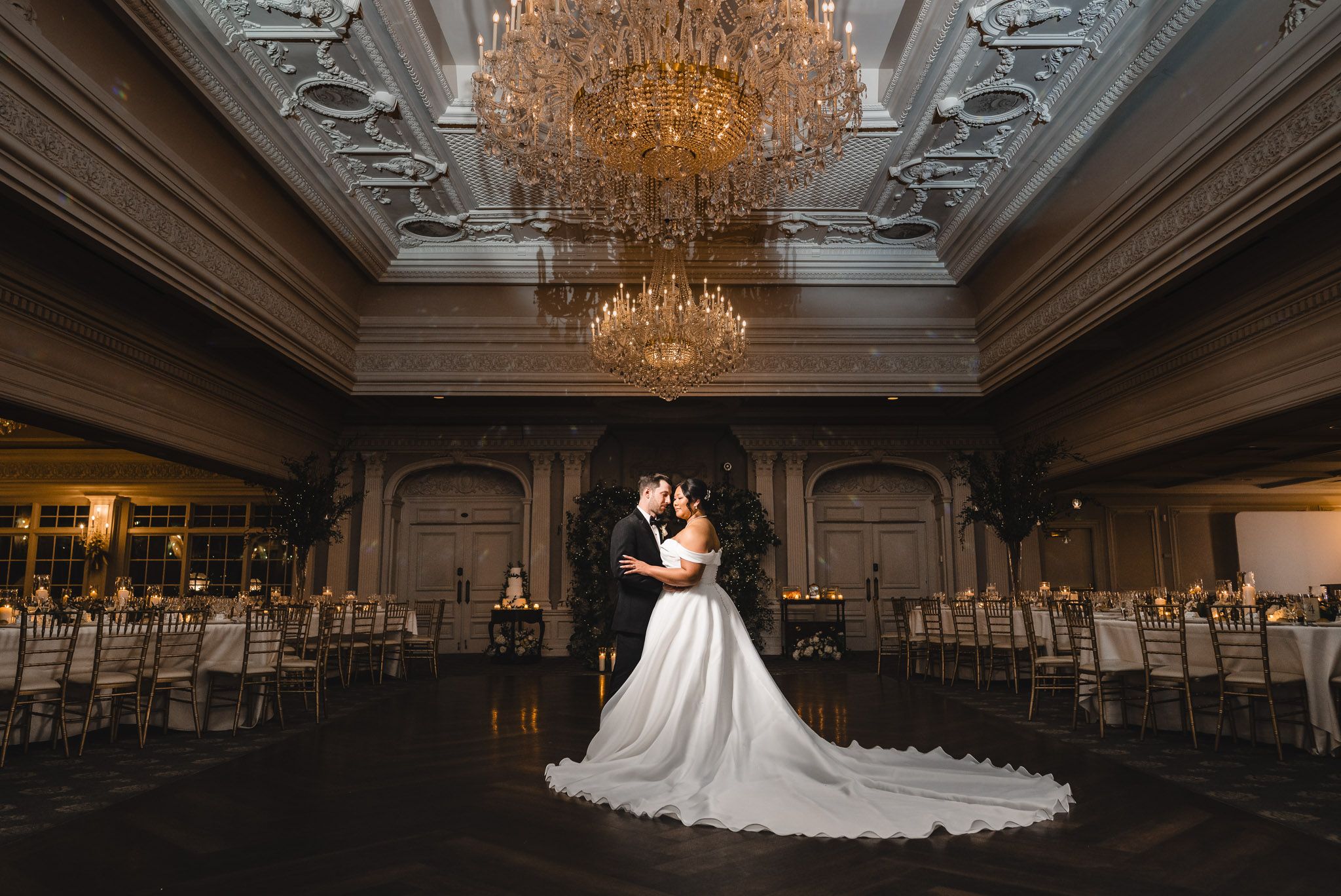 Elegant ballroom wedding reception venue with ornate chandeliers and classic architectural details.