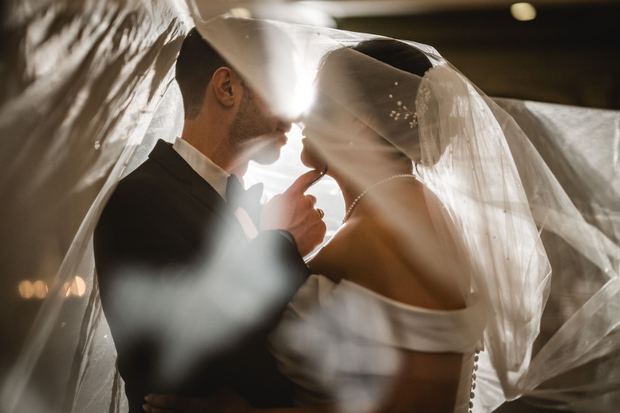 Artistic black and white photo of a flowing wedding veil in dramatic lighting.